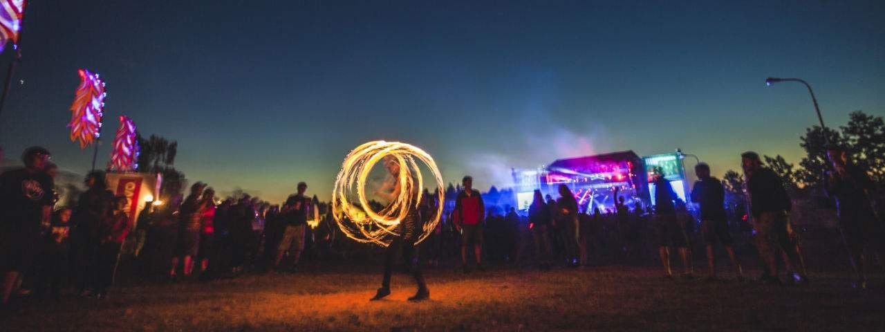 Fire show at the music festival with people standing around in the background.